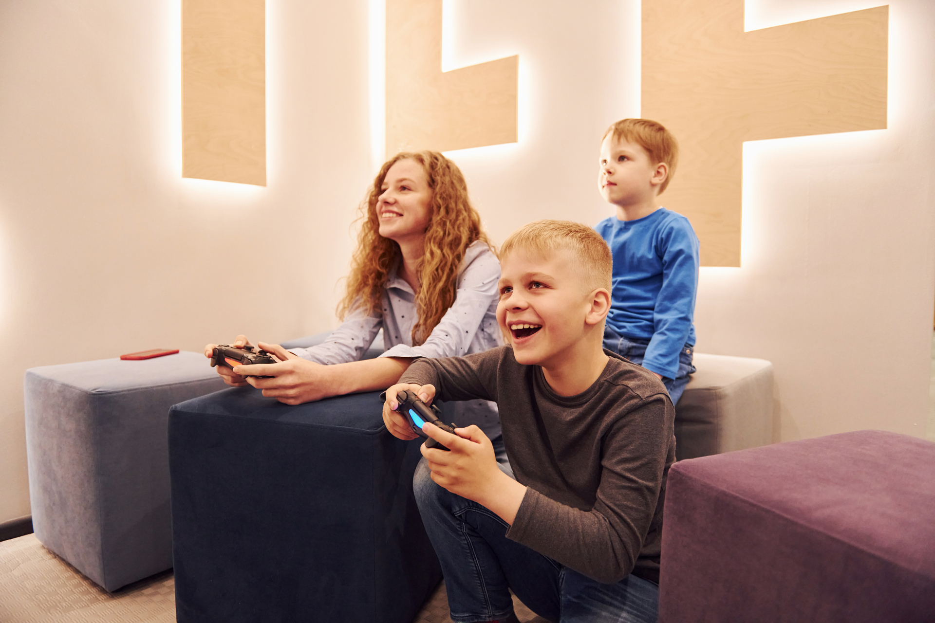 In questa immagine, una madre e i suoi figli stanno giocando a un videogioco sulla PS4 insieme