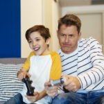 In questa immagine, un padre e suo figlio stanno giocando alla PS4 insieme