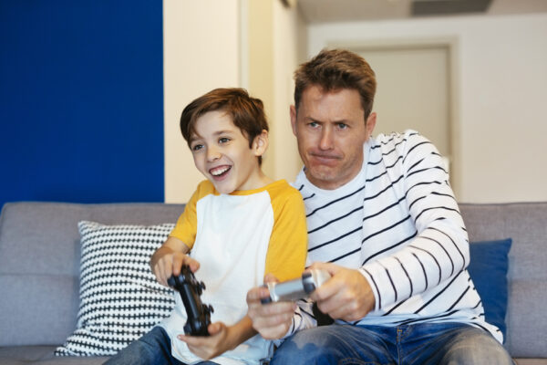 In questa immagine, un padre e suo figlio stanno giocando alla PS4 insieme