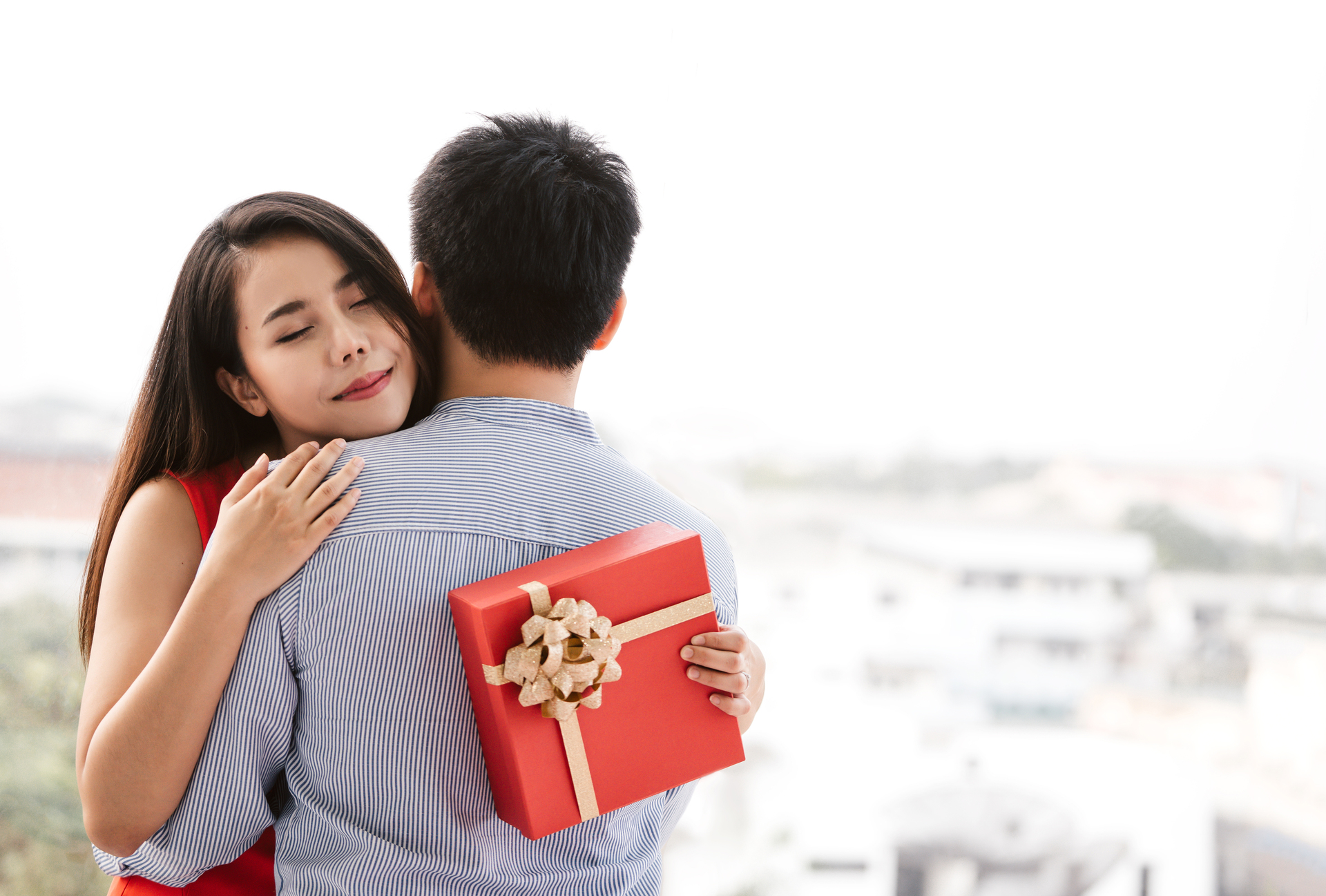 In questa immagine c'è un ragazzo con una ragazza e la ragazza tiene tra le mani un regalo di San Valentino